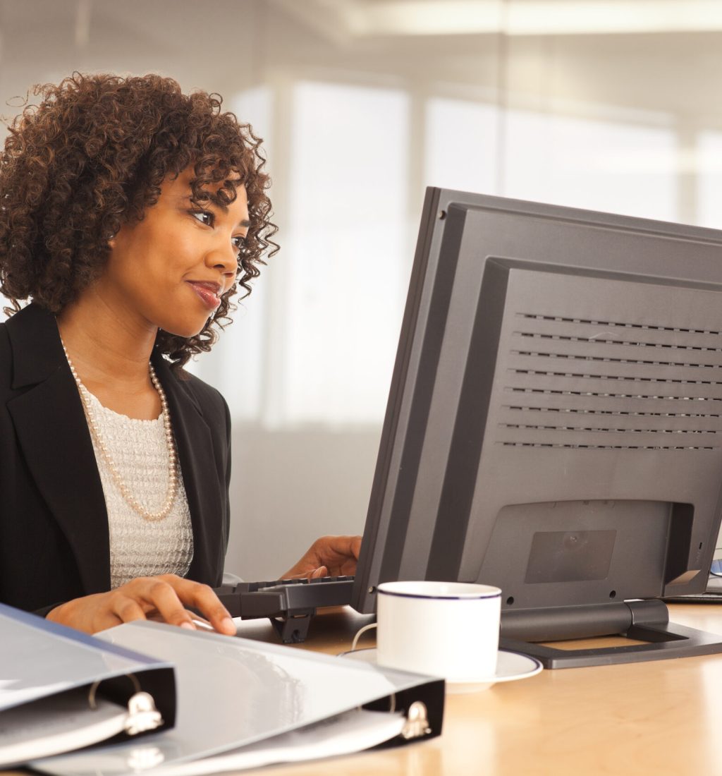 Young businesswoman using computer at desk indoors office building long term care software